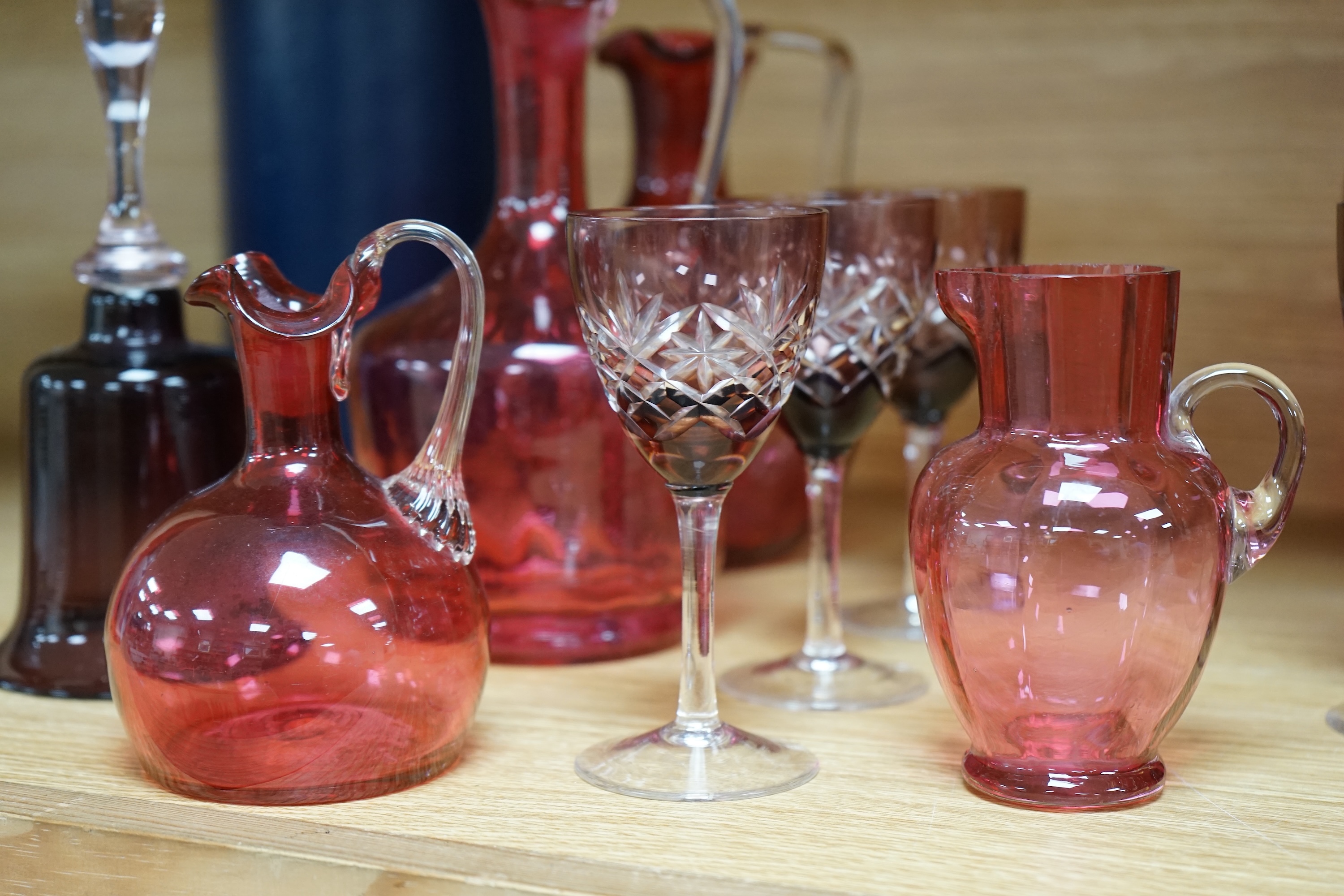 Mixed cranberry glassware to include jugs, glasses, jars and a comport, largest 23cm high. Condition - fair to good